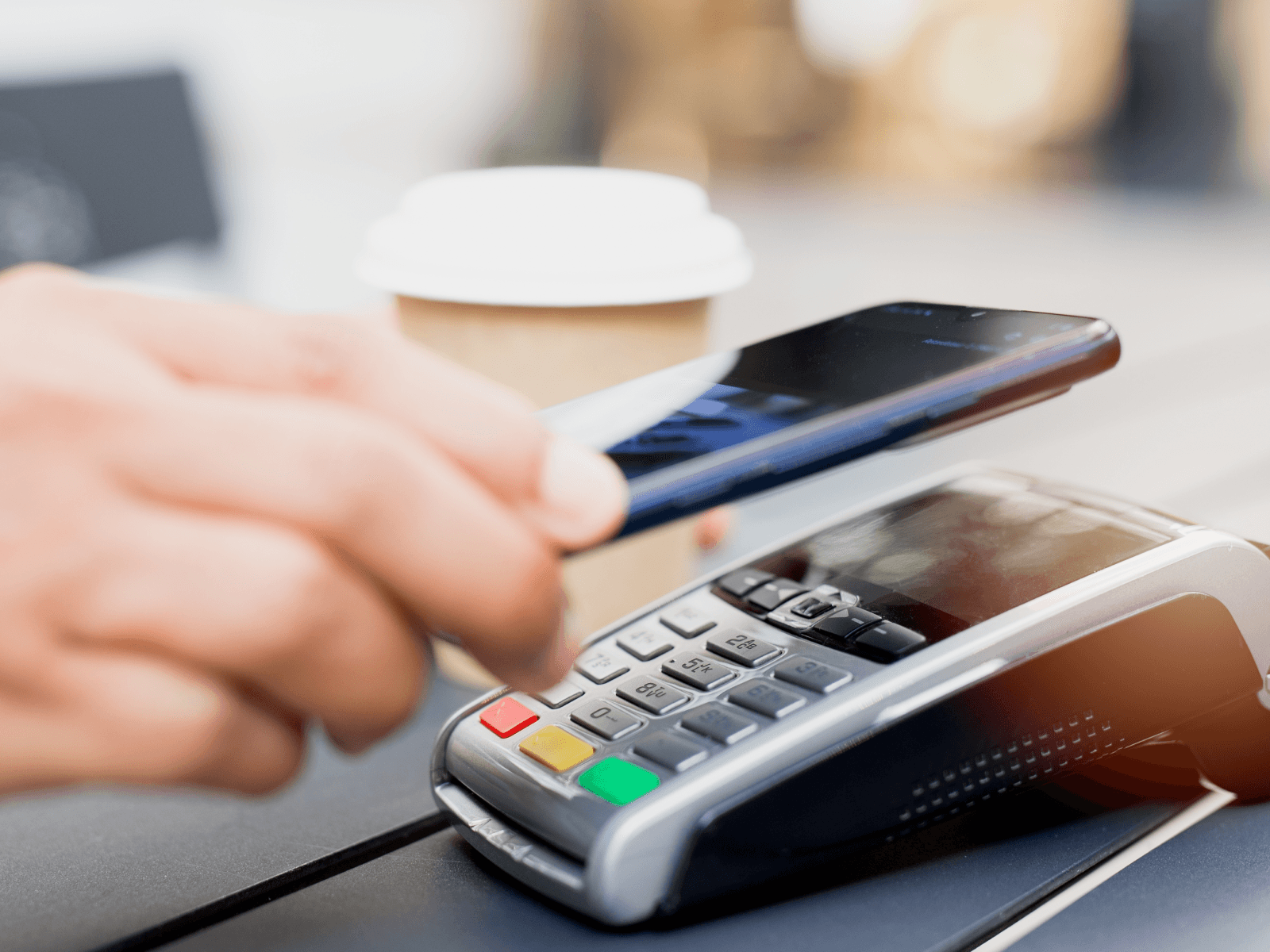 Picture showing a hand with a phone over a payment terminal