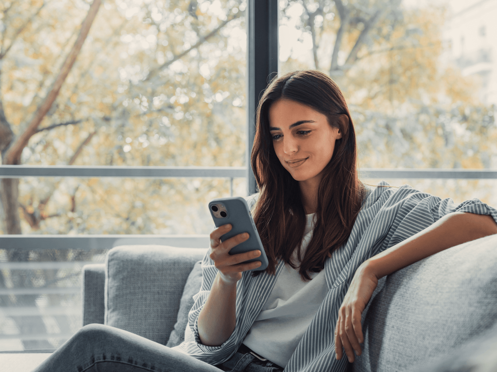 Woman sitting in a couch looking at her phone